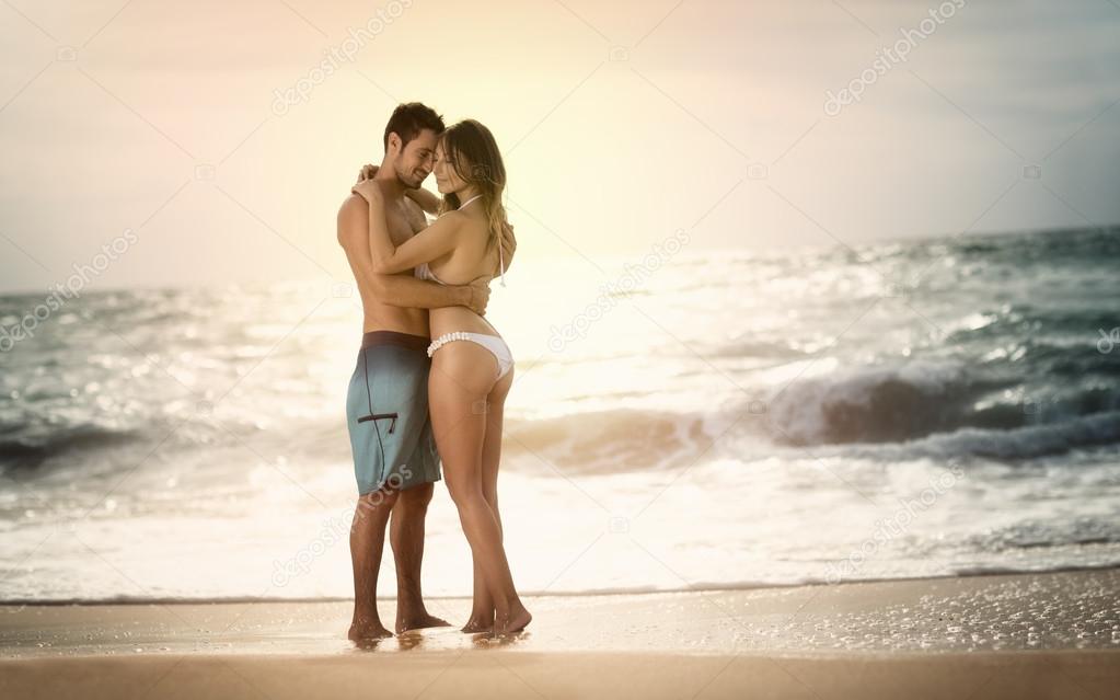 Young beautiful couple in love on the beach on sunset