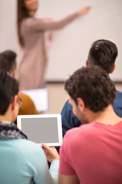 Dos estudiantes viendo la tableta mientras el profesor da una conferencia — Foto de Stock
