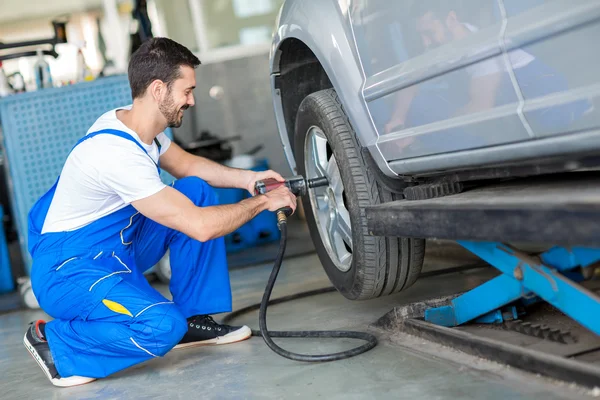 Mechanic changing tyre on car with air wrench — Stock Photo, Image