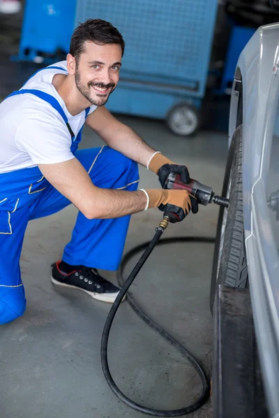 Smiling mechanic repairing car wheel — Stock Photo, Image