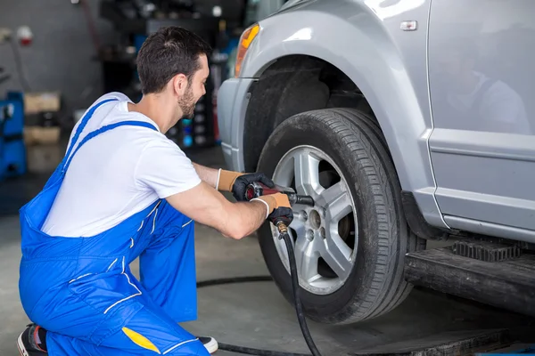 Male mechanic repairing car's wheel — Stock Photo, Image