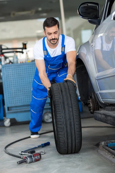 Mechanic repair and  pushing a black tyre — Stock Photo, Image