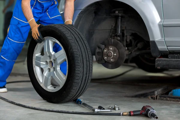 Mecánico cambiando una rueda de un coche moderno — Foto de Stock