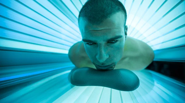 Hombre en cama de bronceado en solarium —  Fotos de Stock