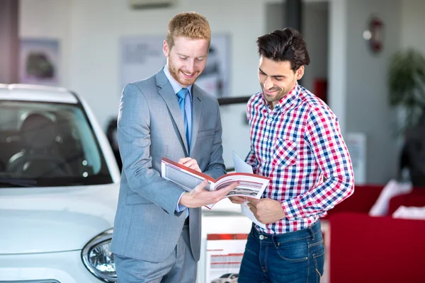 Hombre vendedor y cliente masculino en salón de concesionarios de automóviles — Foto de Stock