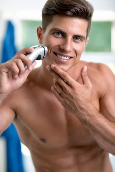 Handsome young man shaving with electric razor — Stock Photo, Image