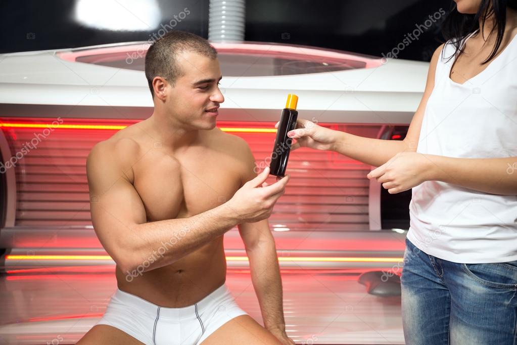 Young man at solarium with girl employee