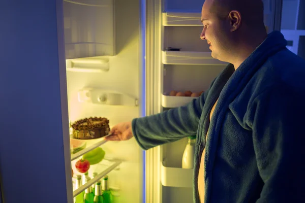 Man at night overstep and take whole chocolate cake from refrige — Stock Photo, Image