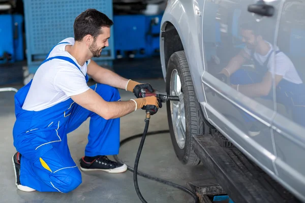 Mężczyzna mechanik naprawy samochodu koło — Zdjęcie stockowe