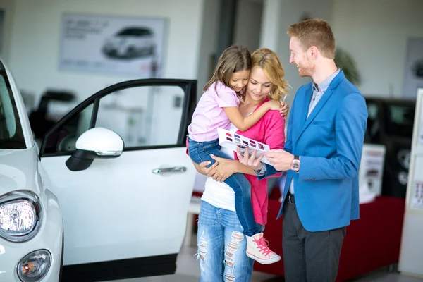 Vrouw met kind in autodealer kijken brochure met sal — Stockfoto