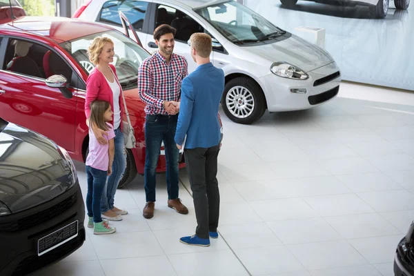 Автомобільний агент вітає сім'ю з покупкою автомобіля — стокове фото