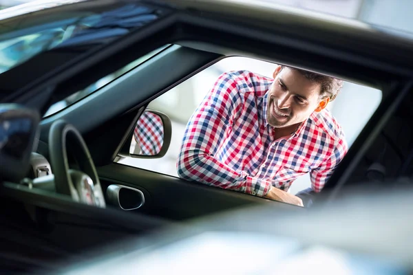 Jonge man op zoek in interieur van een nieuwe auto — Stockfoto