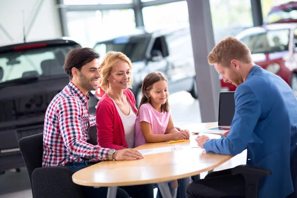 Agente de carro demonstrando carro novo para jovens — Fotografia de Stock