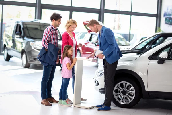 Familia joven escucha con atención concesionarios de coches — Foto de Stock