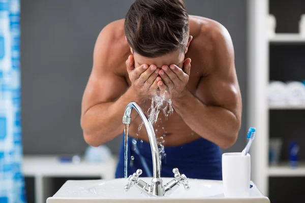 Młody człowiek rozpylanie wody na twarzy po goleniu — Zdjęcie stockowe