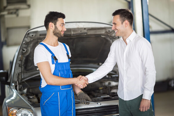 Smiling client and mechanic shaking hands