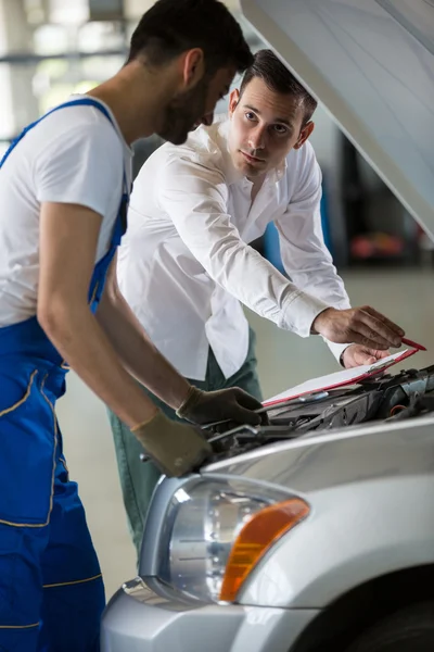 Gerente y mecánico examinar un coche — Foto de Stock