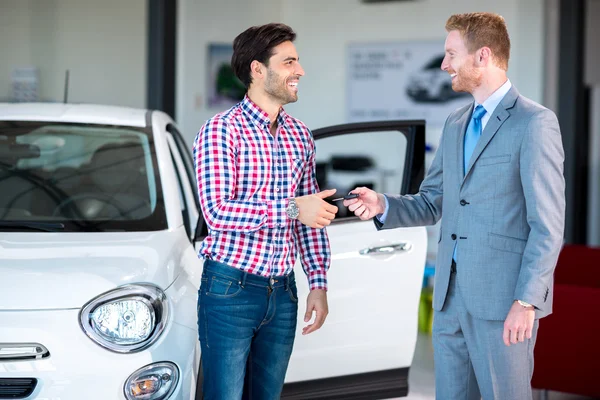 Car dealer giving key of car at young male — Stock Photo, Image