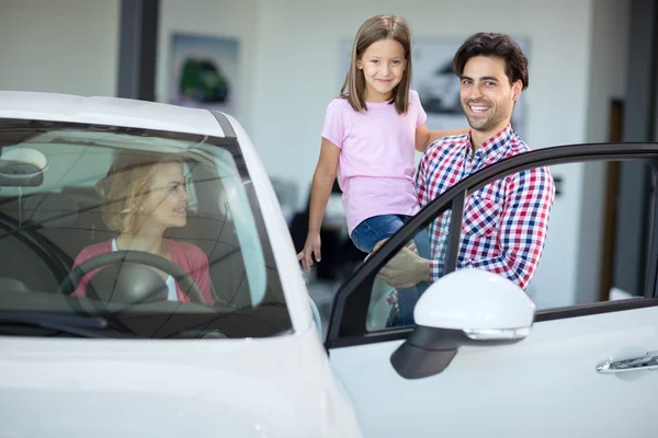 Lyckliga familjen att välja bil i bil utställningslokal — Stockfoto