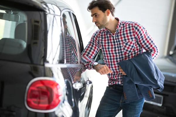 Young handsome customer in car showroom — Stock Photo, Image