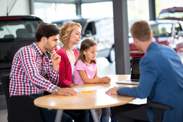 Familia interesada en comprar coche nuevo escucha agente de coche — Foto de Stock