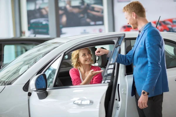 Mulher recebe as chaves de um carro novo de um gerente de vendas — Fotografia de Stock