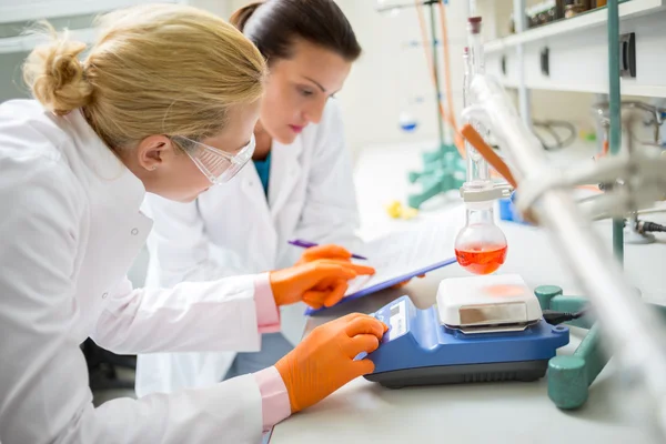 Workers in lab adjusting measuring instrument Stock Photo