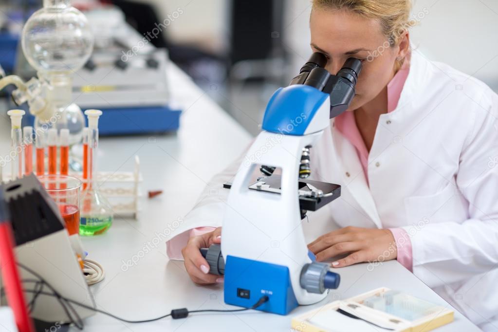 Female chemist exam sample of liquid with microscope