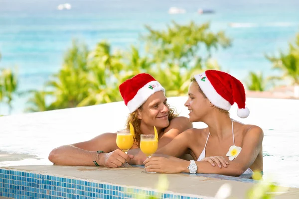 Счастливая молодая пара с Санта-Клаусами наслаждается в бассейне — стоковое фото