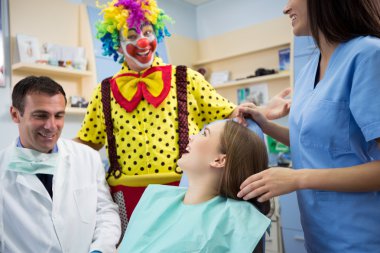 Clown in dental clinic make laugh young girl clipart