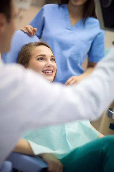 Cliente sorridente na cadeira dental ouvir solução de problema de d — Fotografia de Stock