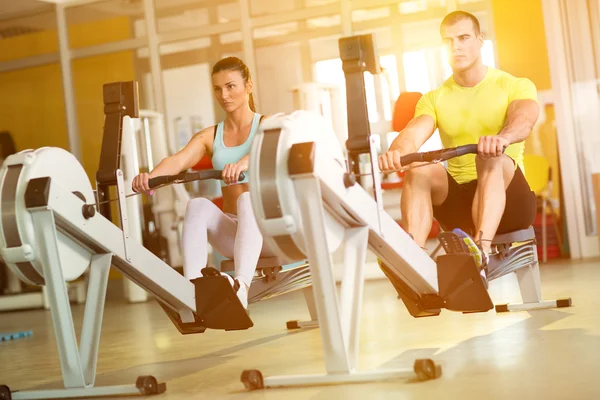 Ajuste pareja en fila máquina en el gimnasio — Foto de Stock