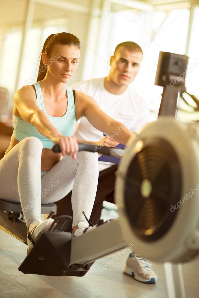 Attractive woman doing exercise on row machine in gym