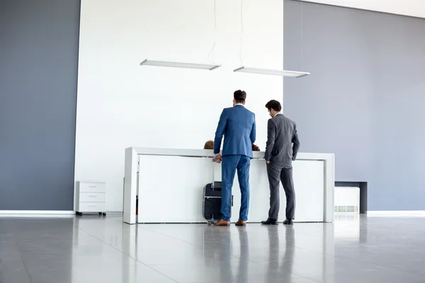 Businessmen check in at reception — Stock Photo, Image