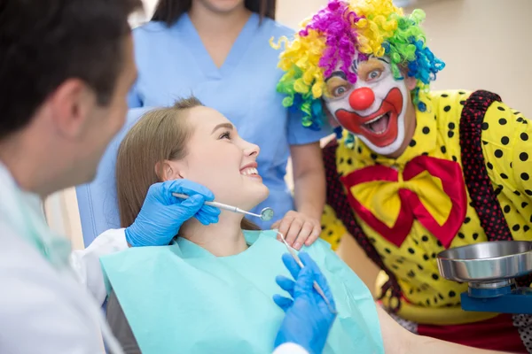 Zabawny clown w Klinika stomatologiczna zwraca uwagę młodego klienta — Zdjęcie stockowe