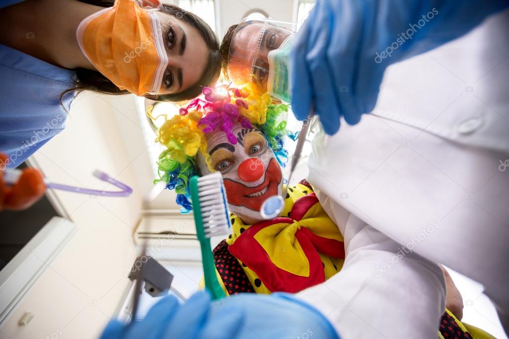Dentist with nurse working in bottom view with clown holding too