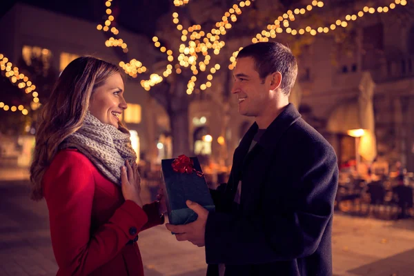 Happy couple with Christmas and New Year gift on street — Stock Photo, Image