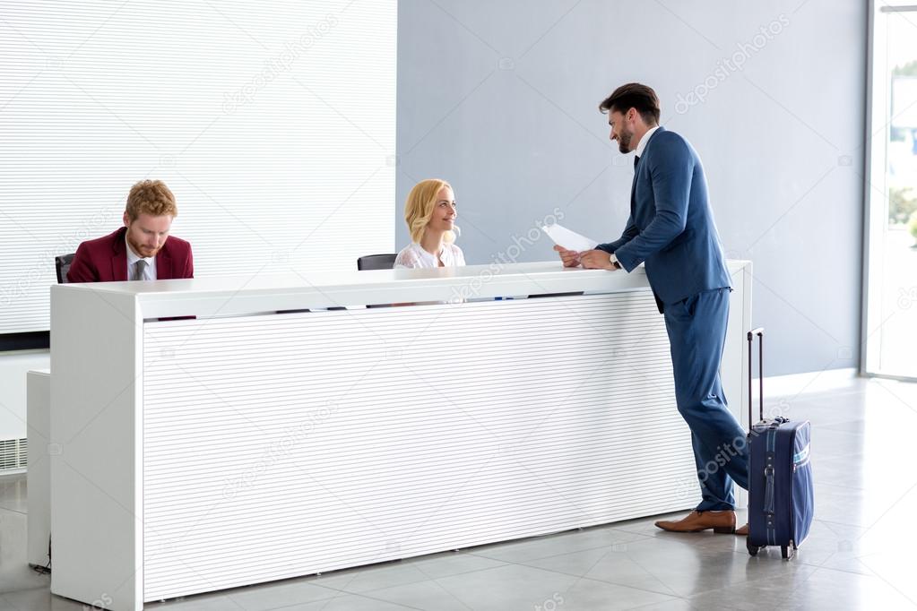 Businessman flirting at reception with female receptionist