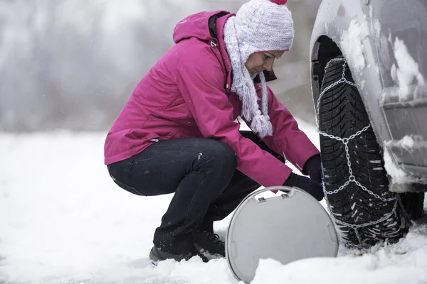 Femme mettre des chaînes de neige — Photo