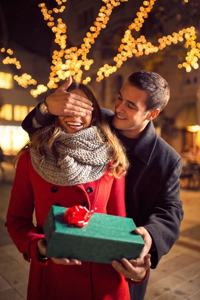 Romantic man standing behind woman with gift on street with Chri — Stock Photo, Image