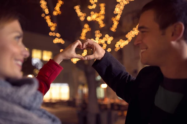 Pareja mirándose el uno al otro y haciendo forma de corazón — Foto de Stock