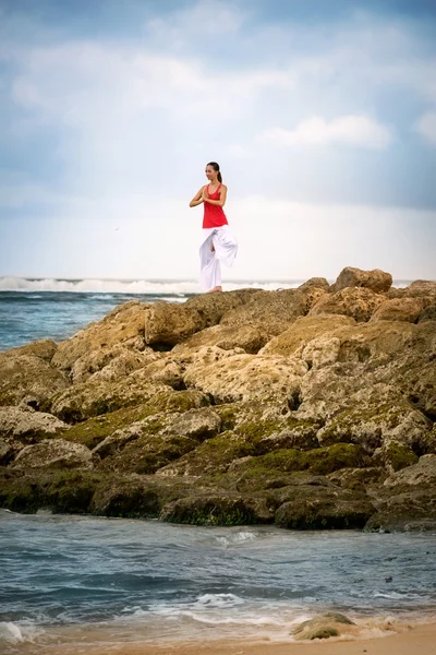 Rustige vrouw in zen moment mediteren op rots in zee — Stockfoto