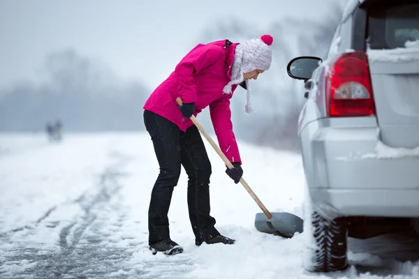 女性が彼女の車の周りの雪をクリーニング ストック写真