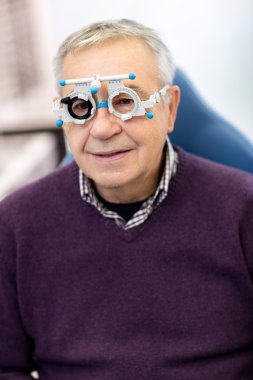 Senior in eye clinic check his sight clipart