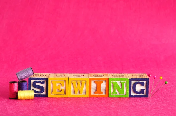 Hilo, alfileres y la palabra coser — Foto de Stock