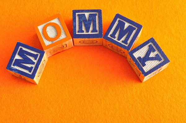 Le mot maman orthographié avec des blocs d'alphabet sur un fond orange — Photo