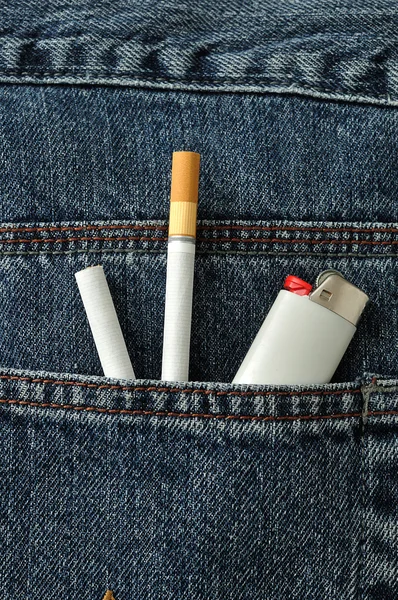 Two cigarettes with a lighter in the back pocket of a denim jeans pants