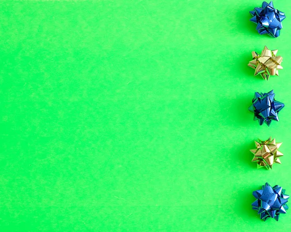 Una fila de lazos de regalo azules y dorados aislados sobre un fondo verde — Foto de Stock