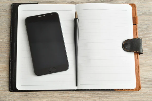 An open notebook displayed with a smart phone and a fountain pen — Stock Photo, Image