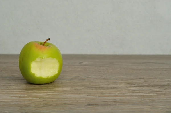 A green apple with a bite taken out — Stock Photo, Image